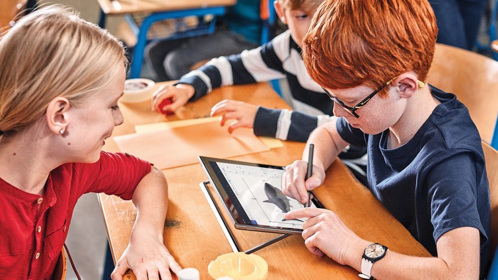 Ein männlicher Grundschüler lernt an einem Tablet in der Schule