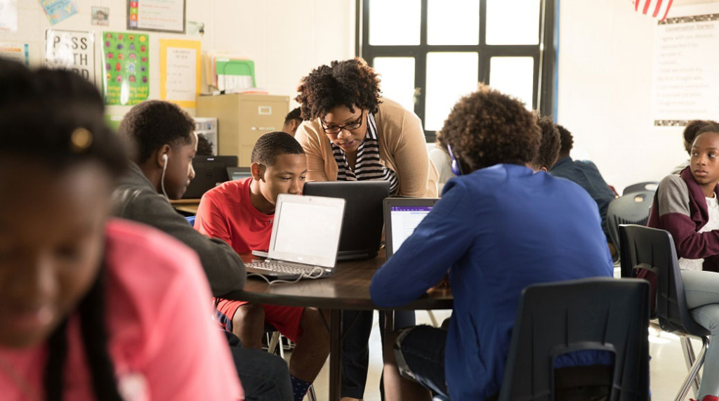 Eine Gruppe von Schülern lernen über Microsoft Teams und wird von einer Lehrerin beaufsichtigt.