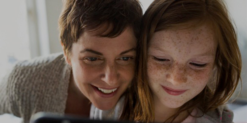 Eine Mutter beugt sich über die Schulter Ihrer Tochter und schaut mit ins Tablet. Eine Mutter unterstützt ihre Tochter bei den MINT Bereichen.