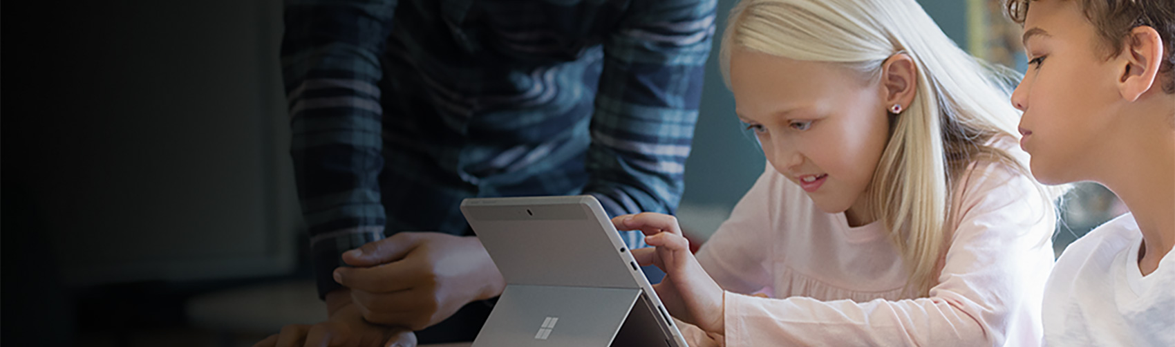 Microsoft Digitalpak(e)t: Innovative Technik für modernes Lernen Ein Lehrer hilft einer Schülerin beim Arbeiten an einem Surface laptop