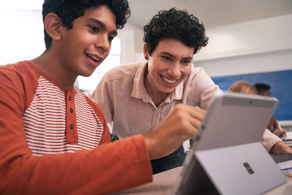 Eine Lehrerin zeigt einem Schüler etwas an seinem Tablet PC