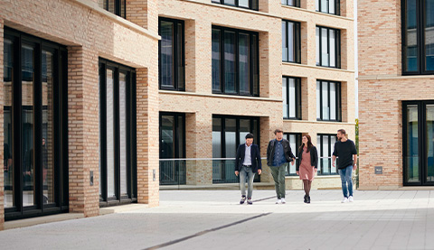 Backsteingebäude und vier junge Personen. 