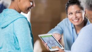 Drei Personen betrachten ein Tablet mit einer Spendenaufforderung. "Make a Difference" und "Spenden"-Button sind sichtbar.
