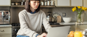 Eine Frau sitzt in der Küche und arbeitet an einem Surface Device Eine Frau sitzt in der Küche und arbeitet an einem Surface Device