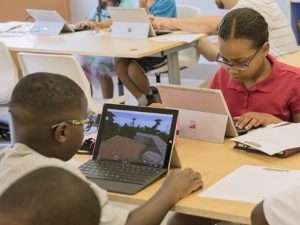 Zwei Kinder spielen im Unterricht Minecraft auf dem Laptop