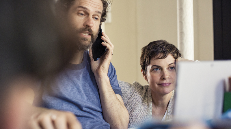 Vater und Mutter in der K&uuml;che mit Telefon und Laptop