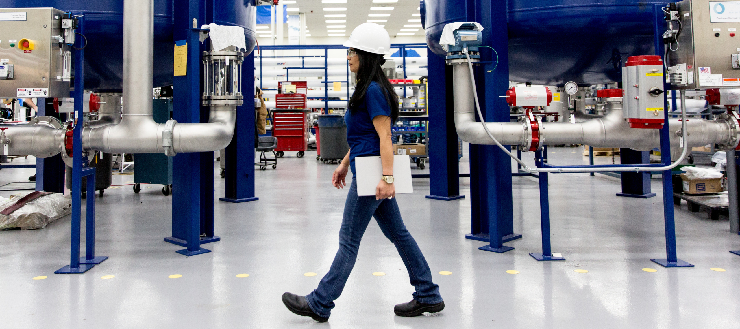 Eine Frau l&auml;uft durch eine Industriehalle