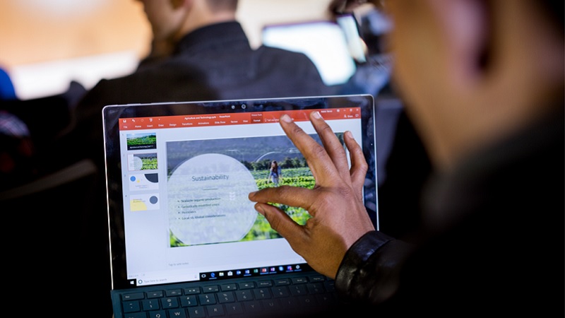 Ein Laptop auf der eine Hand ein Bild mit der Aufschrift Sustainability vergr&ouml;&szlig;ert