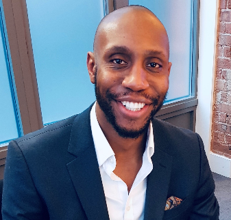 Zephaniah Chukwudum, a man wearing a suit and tie smiling at the camera