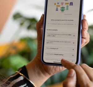 Two hands holding a phone displaying a search prompt using AI