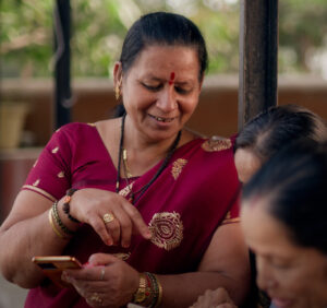 Woman leaning against a pole, looking at her phone in a group of women