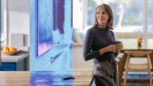 A woman holding a cup and standing near a table.