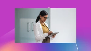 A scientist in a white lab coat writes on a tablet.