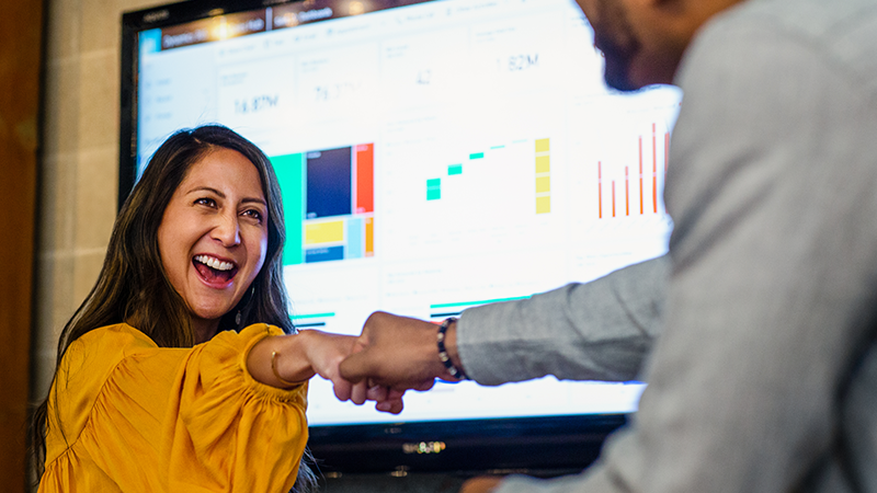 A man and woman laughing together while fist bumping each other