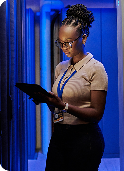 A female technician examines server racks in a modern server room.