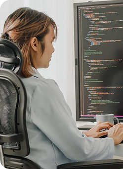 A woman seated at a desk, focused on her computer screen.