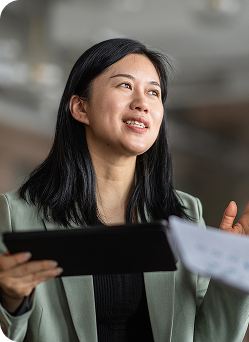 A woman holding a clipboard engages in conversation.