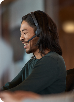 A man wearing a headset sits at a desk, focused on his work.