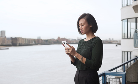 A woman stands on a ferry boat looking at her mobile device