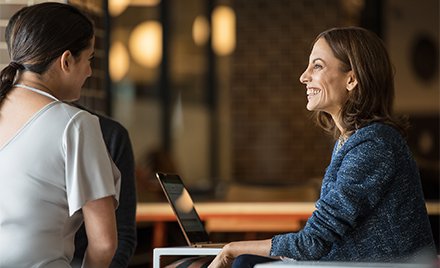 Image of two firstline workers meeting in a meeting room. One has her laptop open