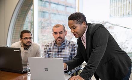 Image of a team of three collaborating over a computer