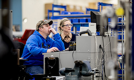 Image of two firstline workers looking at a computer monitor