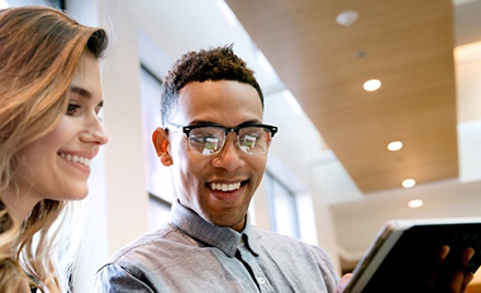 Two coworkers look over a document on a tablet