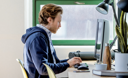 Image of a worker sitting at his desk, hands hovering over his keyboard
