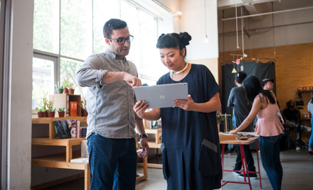 Image of two coworkers looking at a tablet