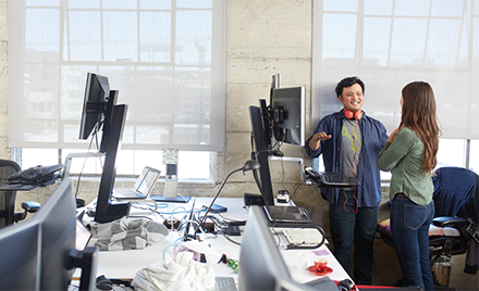 Image of two coworkers meeting next to a computer in their office