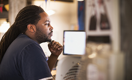 Image of a tech worker stroking his beard and looking at a computer monitor