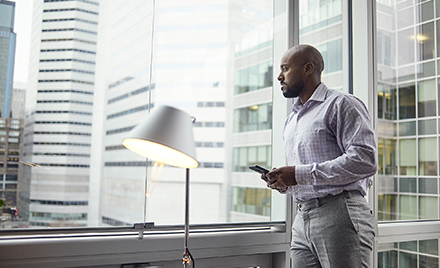 Image of a worker looking up from his phone to gaze out a window