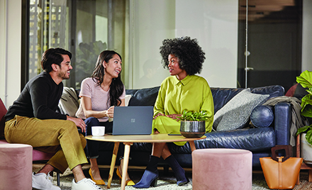Image of three colleagues chatting on a couch at work