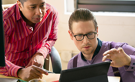 Two co-workers collaborating on a project on a laptop PC