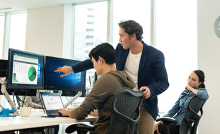 Image of two workers collaborating at a PC