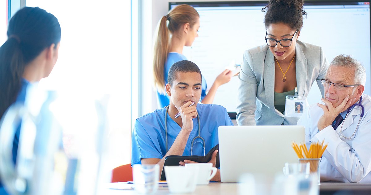 Image of doctors and nurses surrounding a laptop
