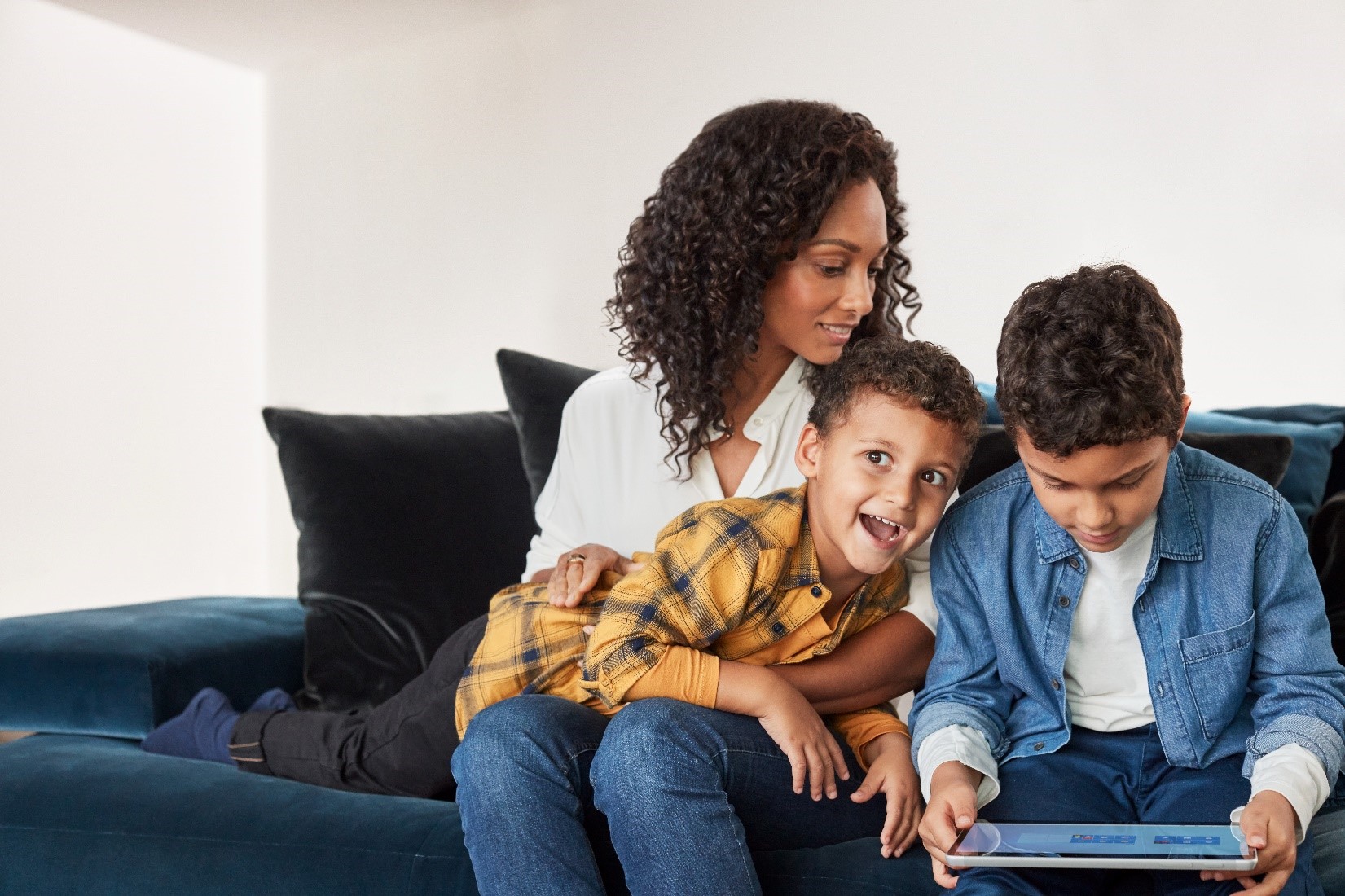 A family on a couch, one child holding a laptop