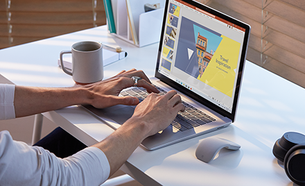 Photograph of worker on Surface Laptop 3 in PowerPoint with Surface Mouse and Surface Headphones