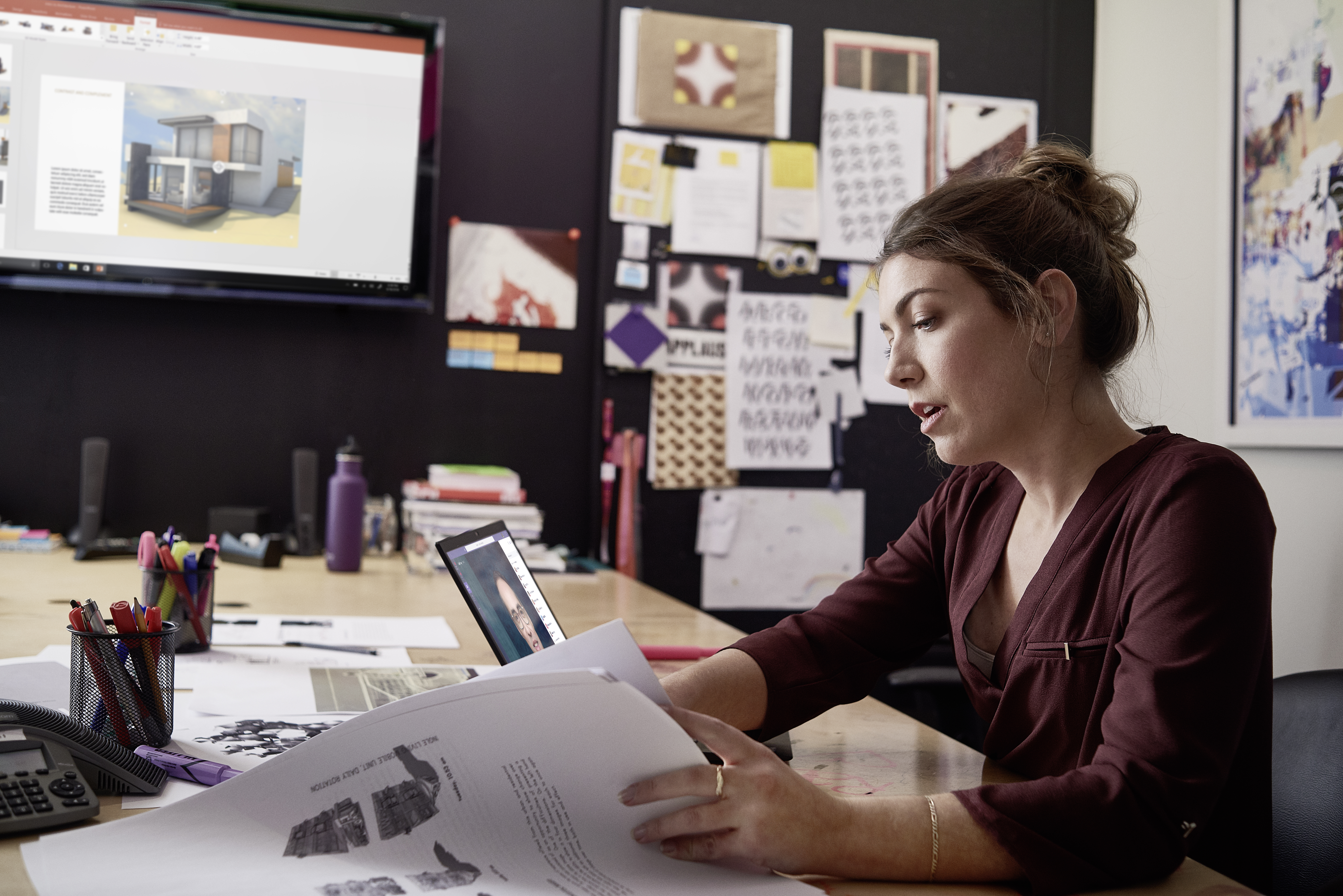 Small business professional working on designs using devices running PowerPoint and Microsoft Teams