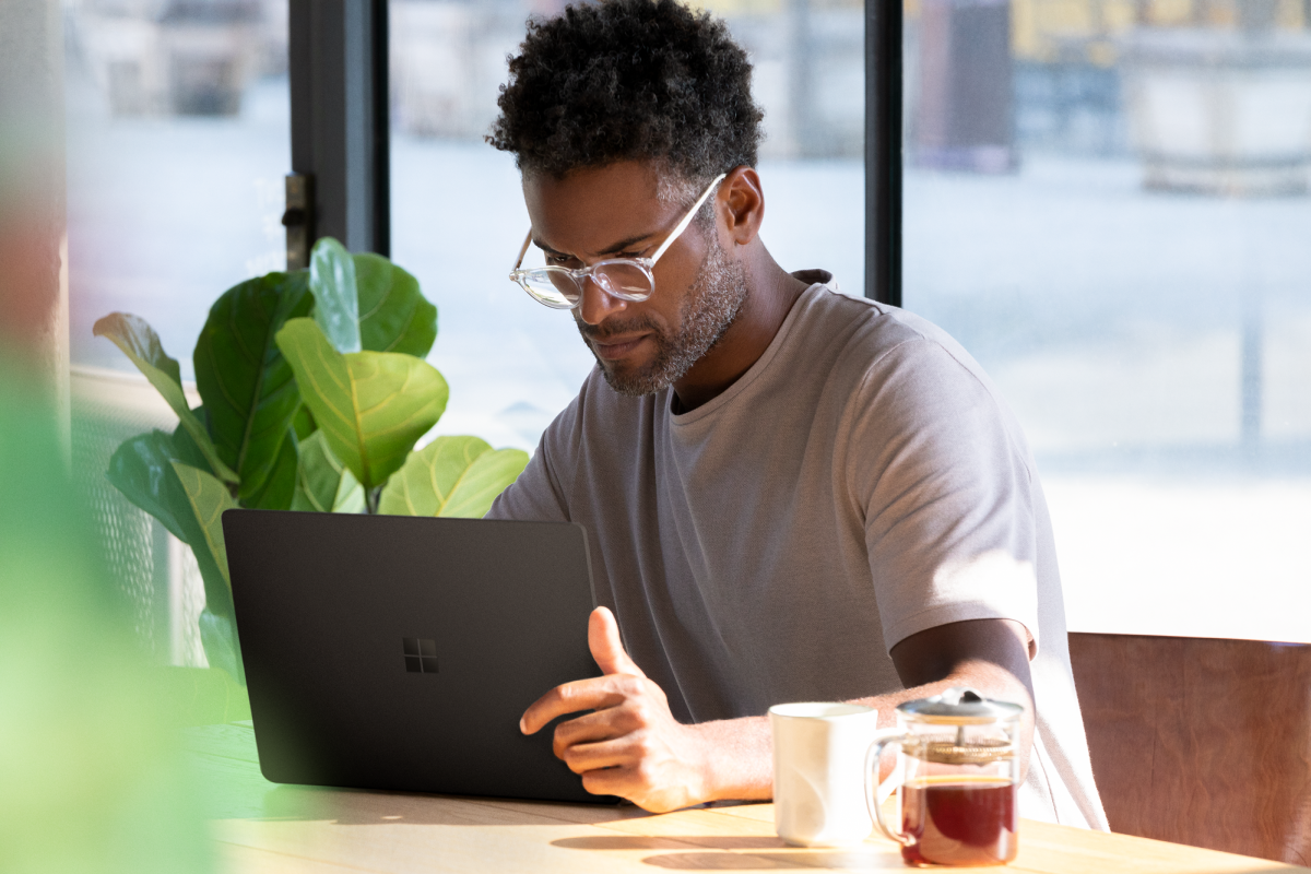 Picture of a man seated at a table, looking down at a computer