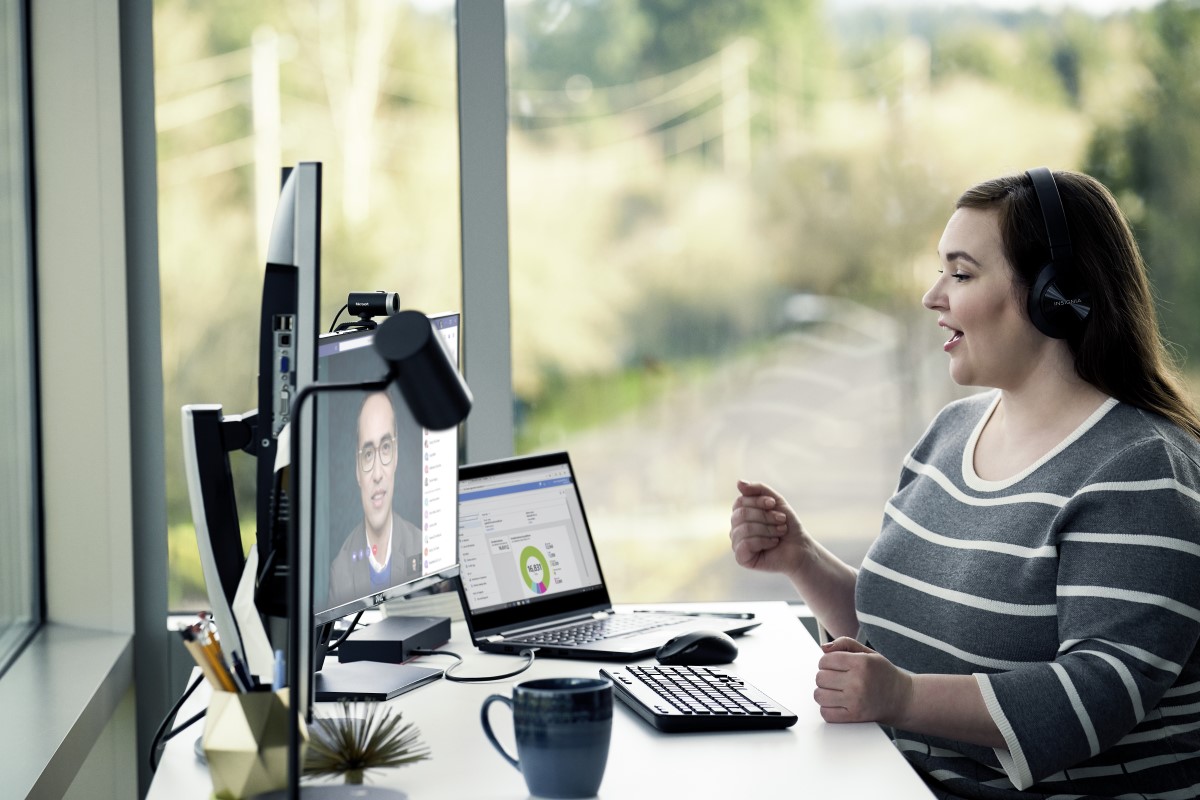 Female enterprise employee working remotely from her home office, chatting with a headset on