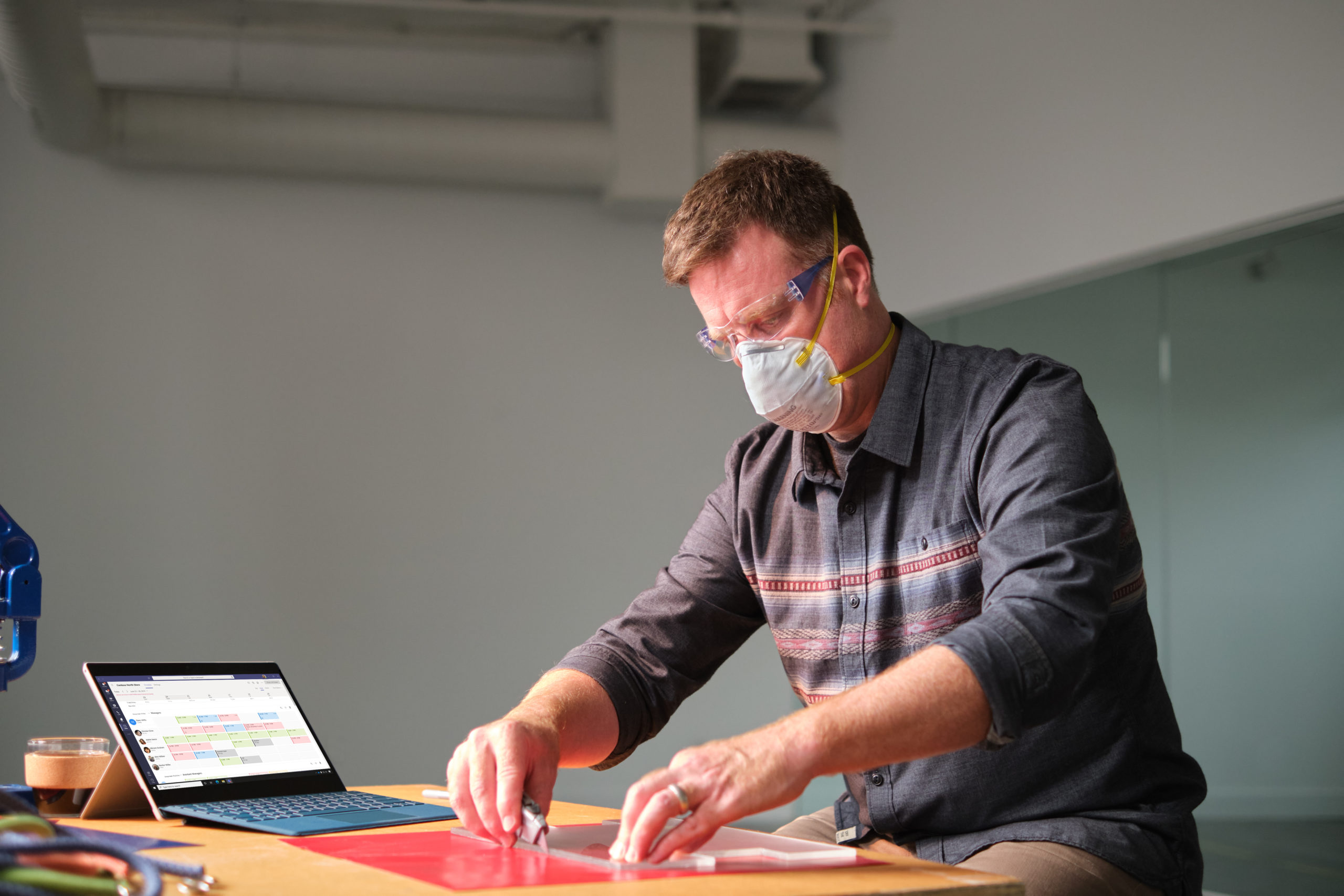 Manufacturing business owner wearing a mask and reviewing schedule in Shifts within Microsoft Teams
