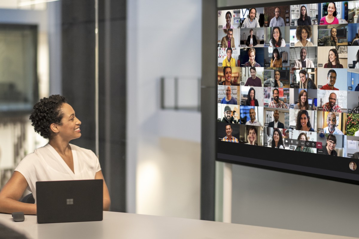 Adult female meeting in a conference room while using Microsoft Teams Together Mode on a Surface Hub 2S 85” device