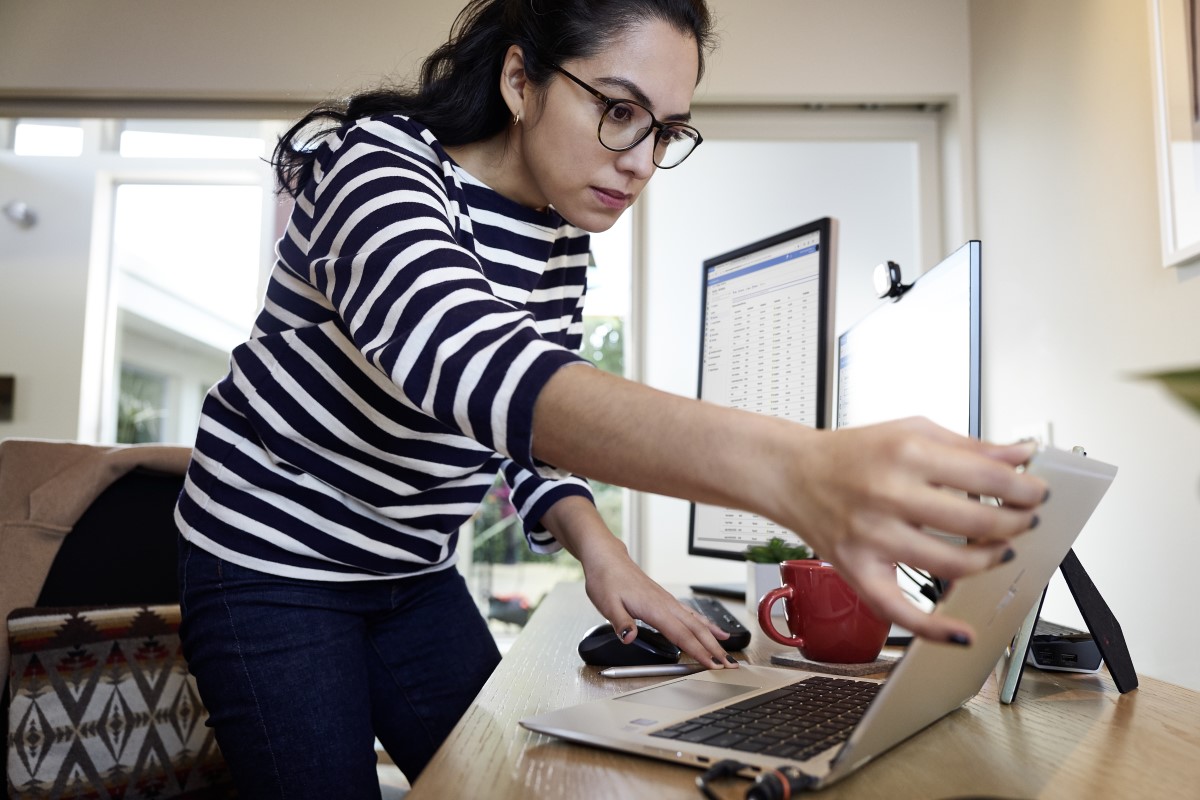 Female working remotely from her home office on an HP Elitebook device, standing at her desk