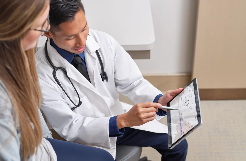 Doctor using mobile tablet to discuss treatment options with patient