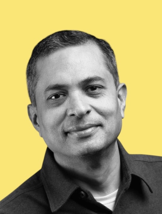 Black and white headshot of Srini Raghavan with yellow background.