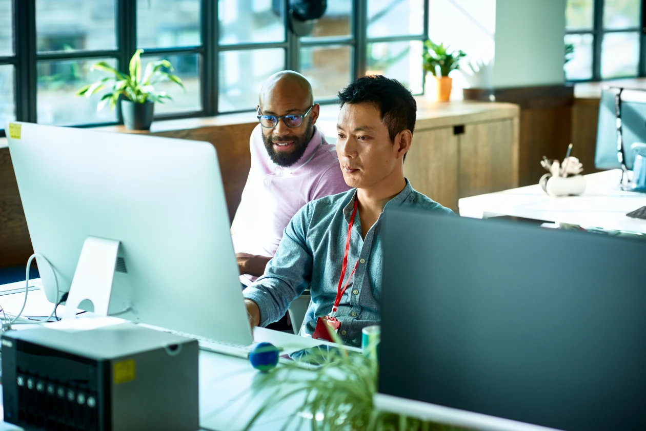A group of men looking at a computer screen in an office