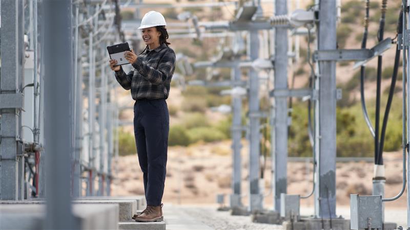 Field engineer inspects electrical substation on a wind farm using remote assist with a Surface tablet.