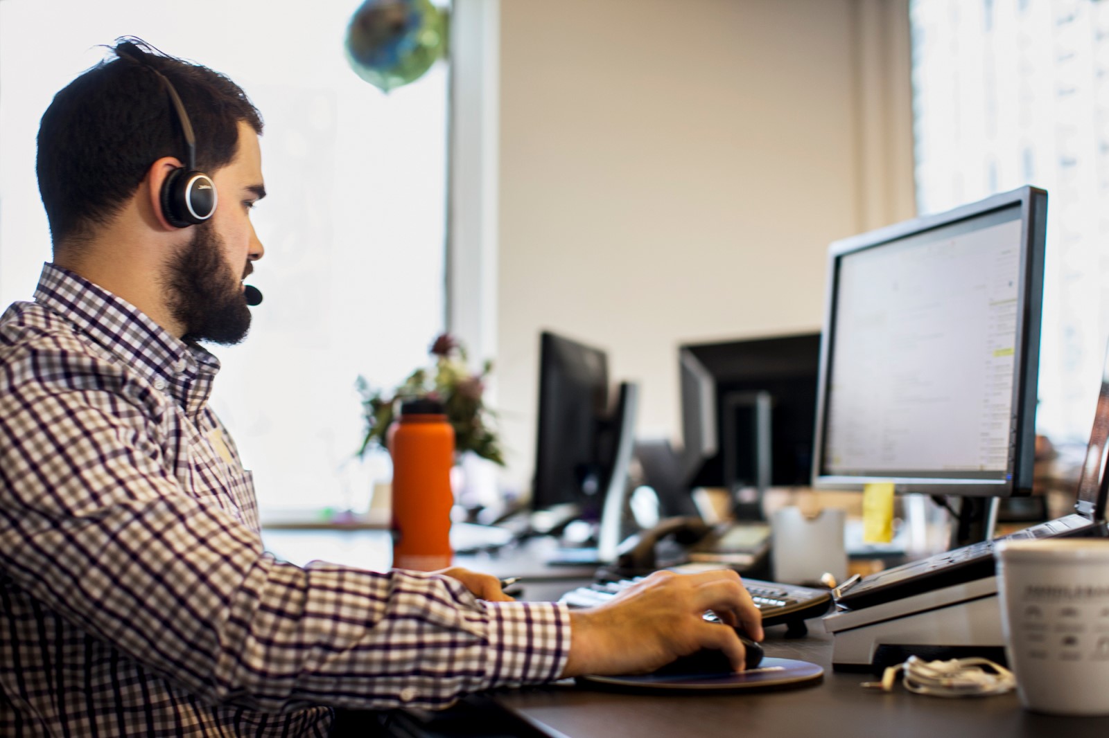 Man sitting at a desk in front of a computer, wearing a headset.