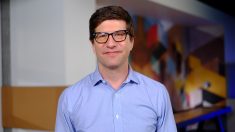 a man wearing glasses and smiling at the camera